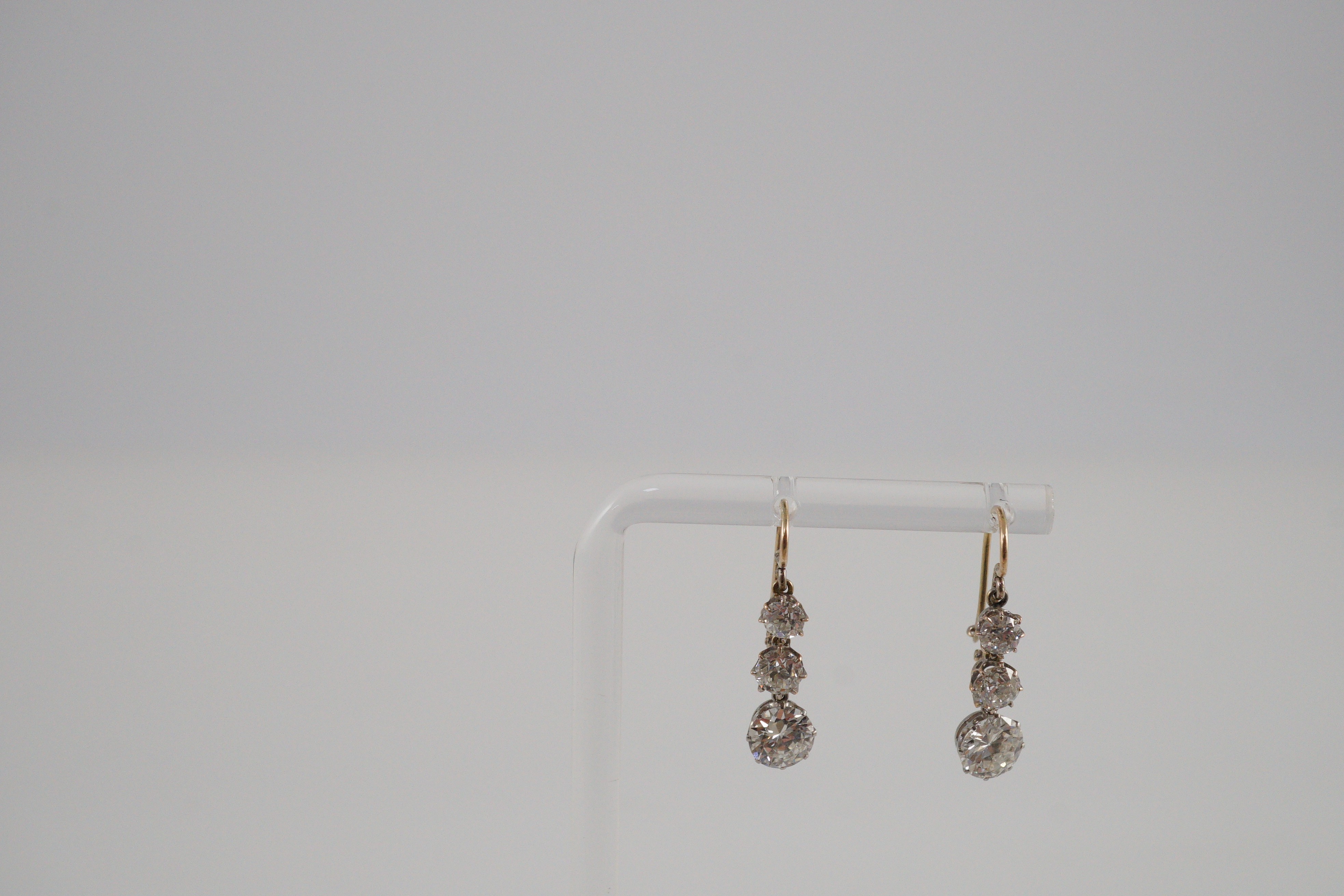 A pair of early to mid 20th century gold, platinum and graduated three stone diamond set drop earrings